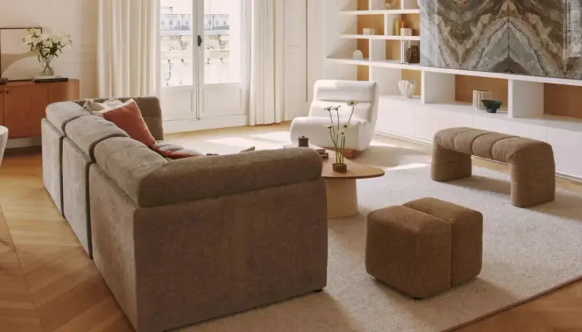 Un salon lumineux avec un canapé modulable, des fauteuils confortables et une banquette design. Un **intérieur contemporain chaleureux** invitant à la détente.