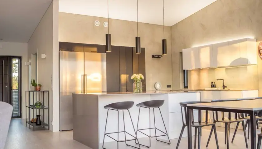 Cuisine lumineuse couleur, avec îlot central, tabourets, réfrigérateur en inox et armoires murales.