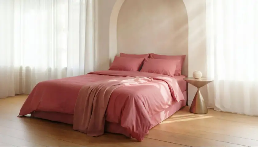 Lit rose avec couvre-lit et coussins. Le polycoton, malgré son aspect doux, peut avoir un inconvénient : il retient la chaleur.