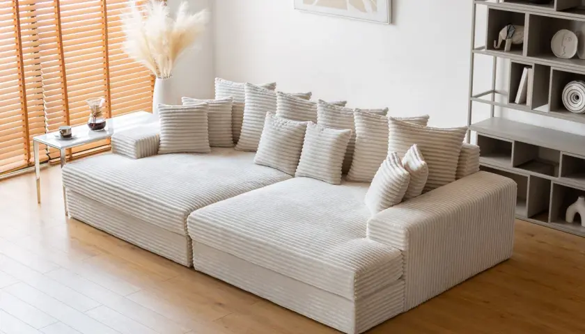 Canapé modulable blanc côtelé, offrant une grande profondeur pour un confort optimal. Des coussins moelleux invitent à la détente.