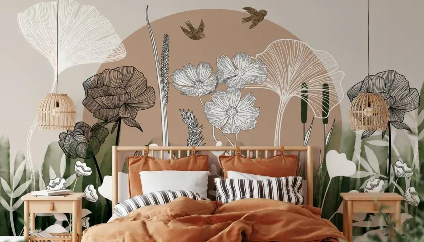 Une chambre romantique moderne avec une fresque murale botanique. Le lit est paré de linge de lit ocre et de coussins rayés.