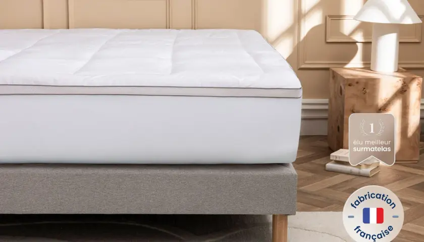 Un surmatelas blanc moelleux sur un sommier gris. Idéal si votre matelas est trop dur que faire ? Fabrication française.