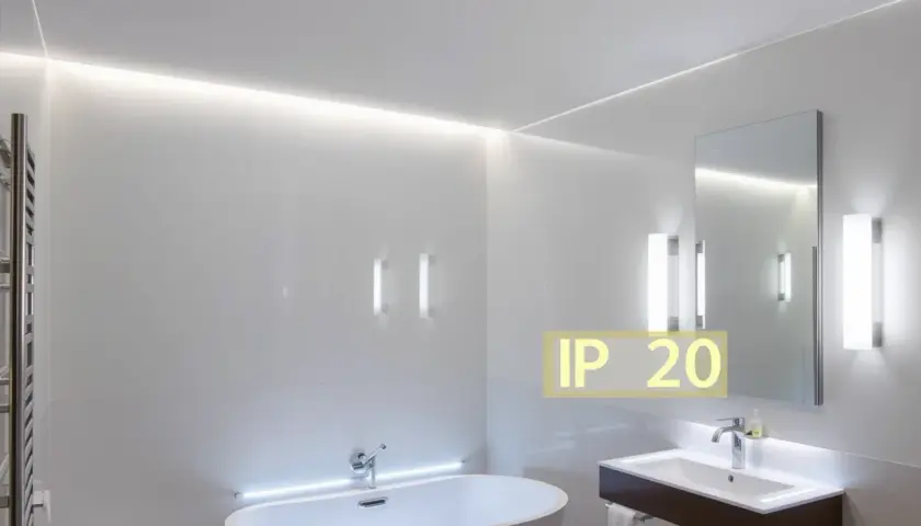 Salle de bain moderne avec baignoire, lavabo et miroir. L'éclairage subtil met en valeur le design épuré. Le texte "IP 20 signification" indique la protection contre les corps solides.