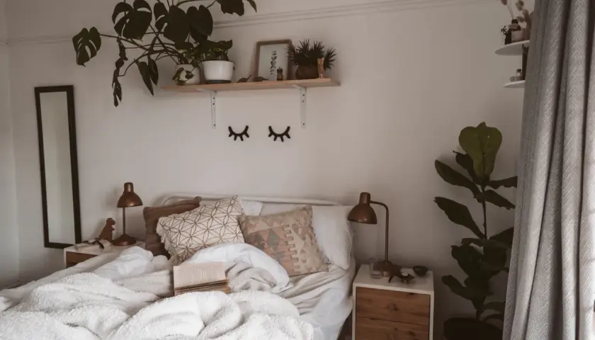 Lit, douillet et plein de verdure, ce lit invite à la détente. Une belle **déco chambre nature** avec des plantes luxuriantes et des coussins texturés.