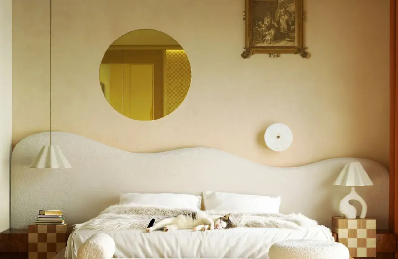 Un chat dort sur un lit douillet. Le beige va avec le blanc, le bois et les touches dorées, créant une ambiance chaleureuse.