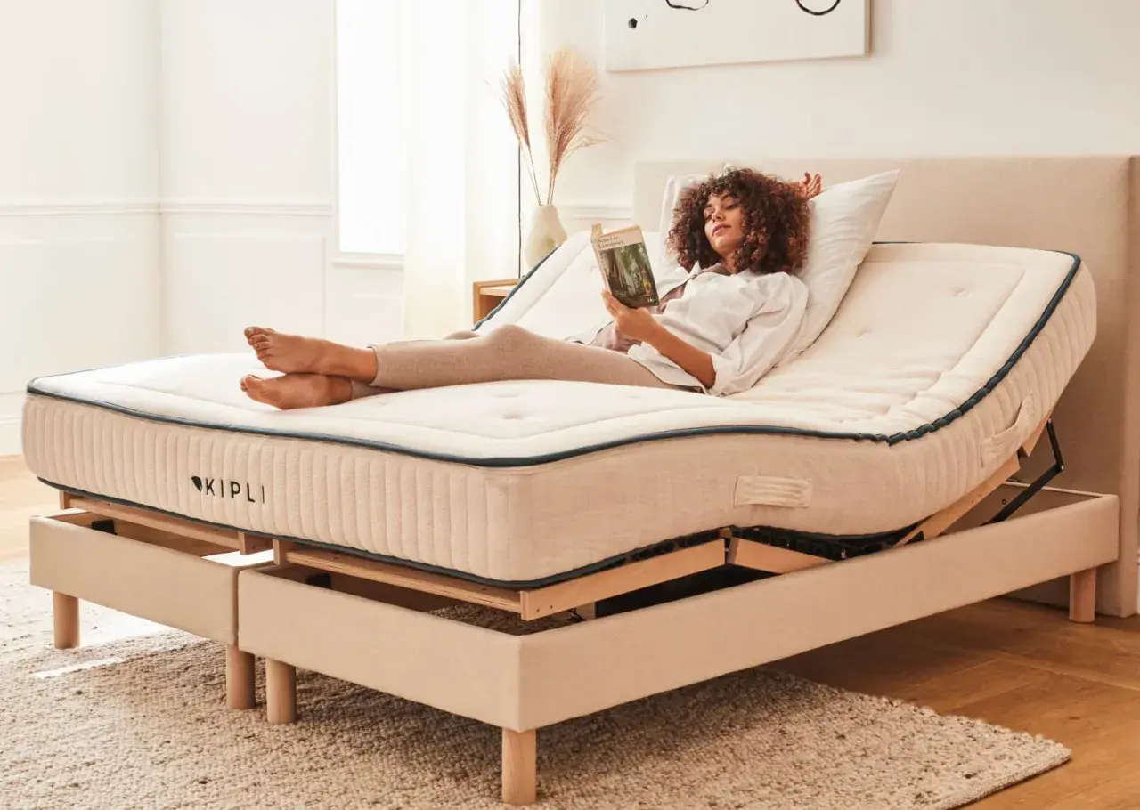 Femme lisant sur un lit électrique réglable. Avantage inconvénient lit électrique : confort personnalisé pour la détente.