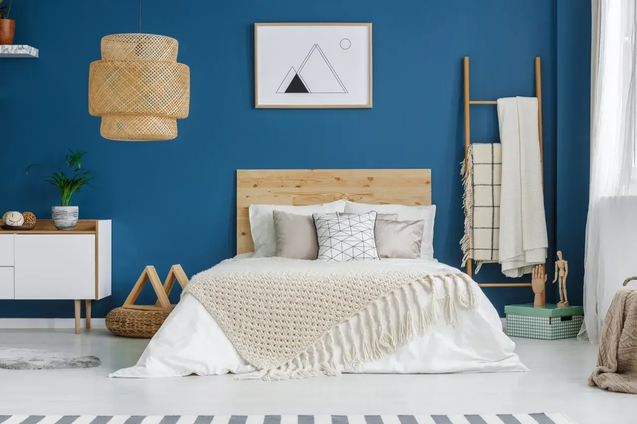 Une chambre bleu et beige avec un lit douillet, une lampe en rotin et une décoration murale minimaliste.