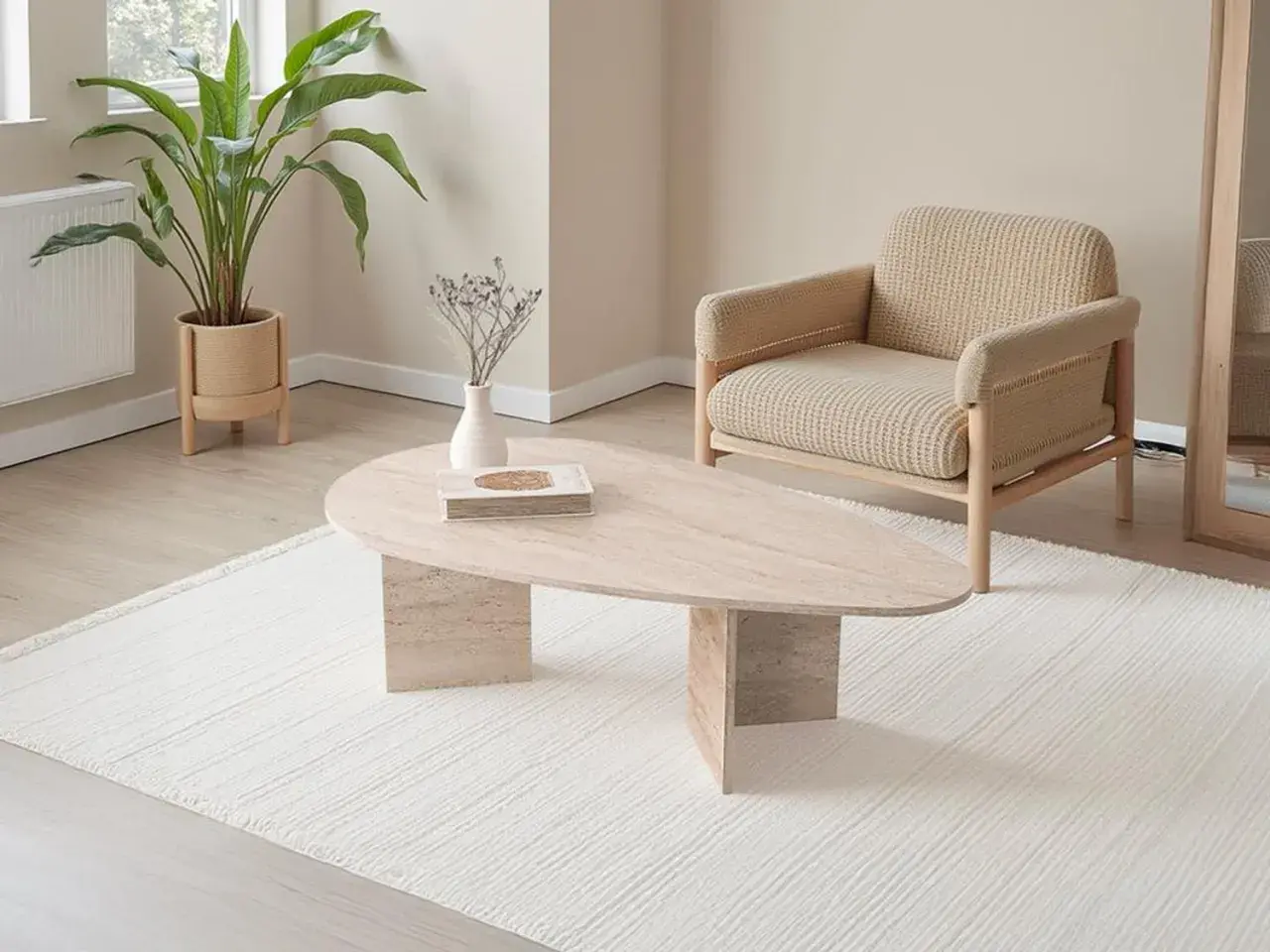 Table basse ovale en travertin, avec une plante verte et un fauteuil en tissu beige.