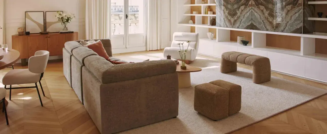 Un salon lumineux avec un canapé modulable, des fauteuils confortables et une banquette design. Un **intérieur contemporain chaleureux** invitant à la détente.