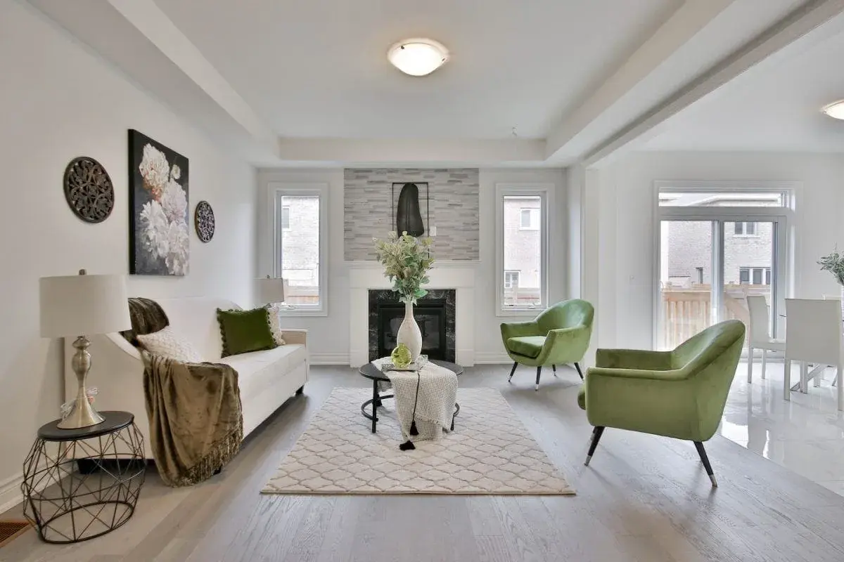 Salon moderne avec canapé blanc, fauteuils verts et cheminée. Une belle idée déco moderne pour un intérieur lumineux.