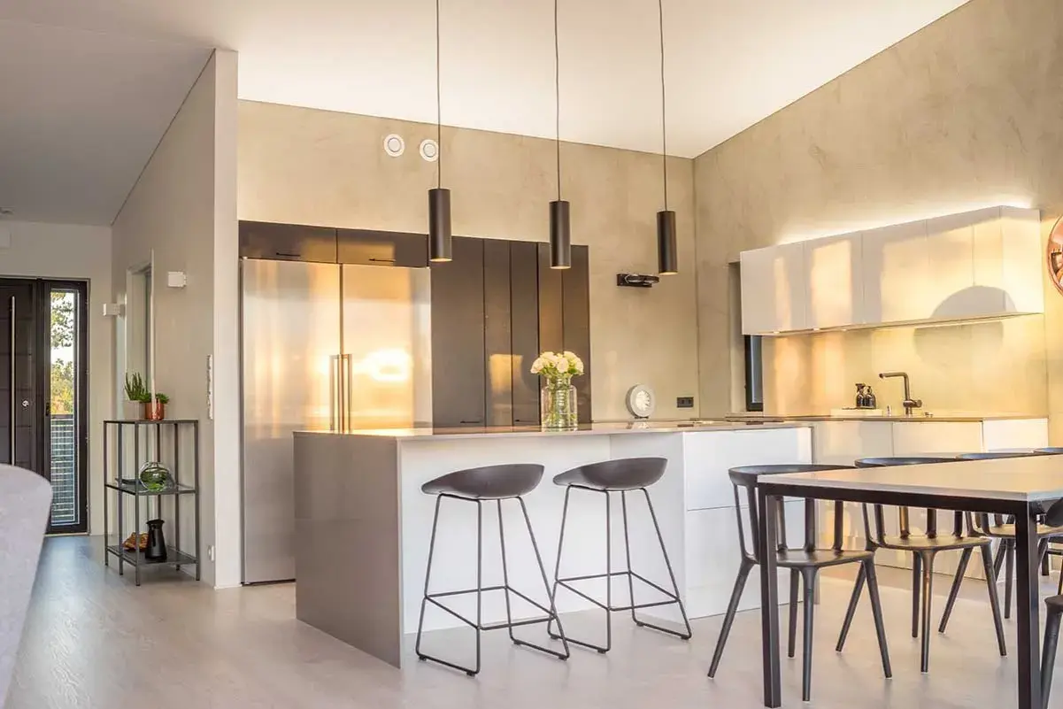 Cuisine lumineuse couleur, avec îlot central, tabourets, réfrigérateur en inox et armoires murales.