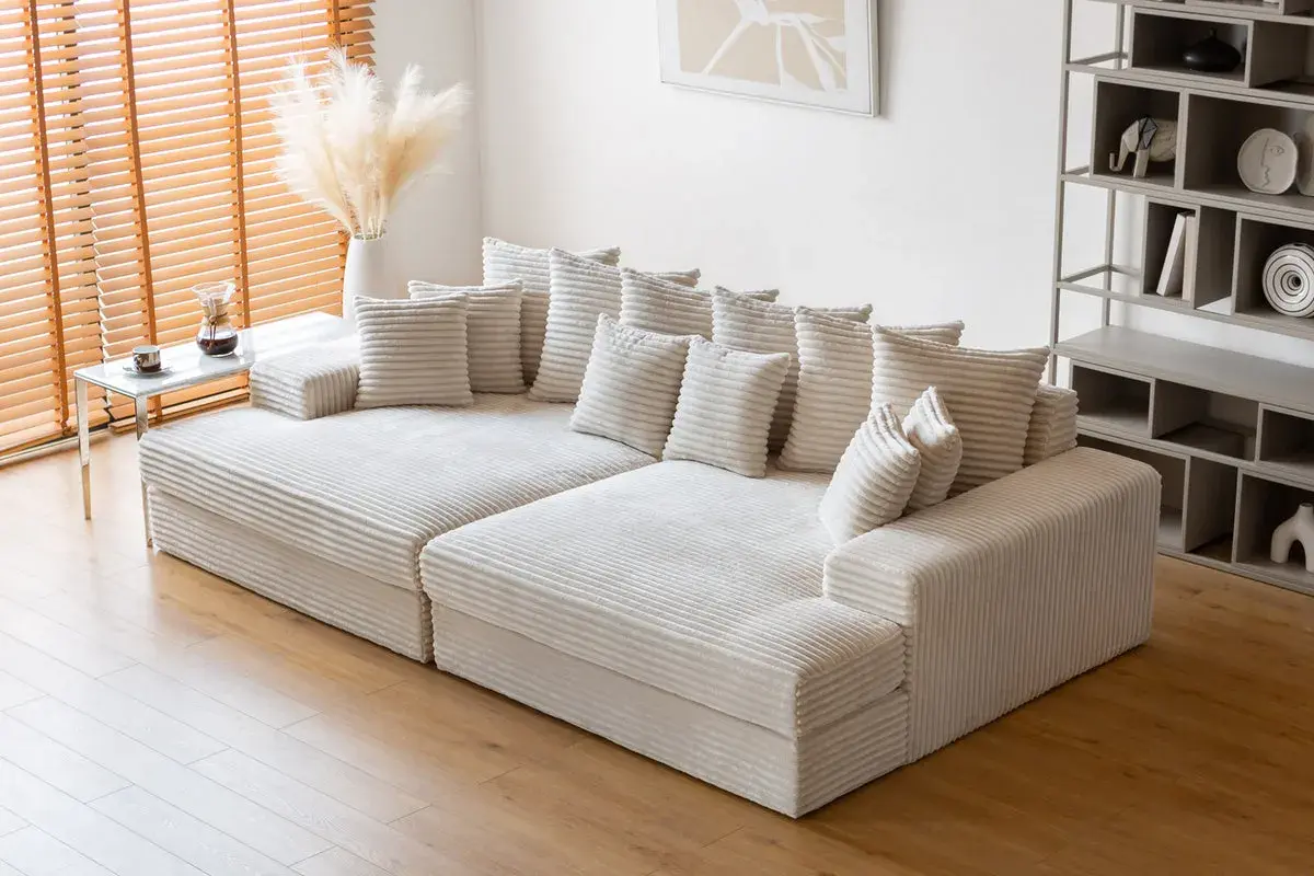 Canapé modulable blanc côtelé, offrant une grande profondeur pour un confort optimal. Des coussins moelleux invitent à la détente.
