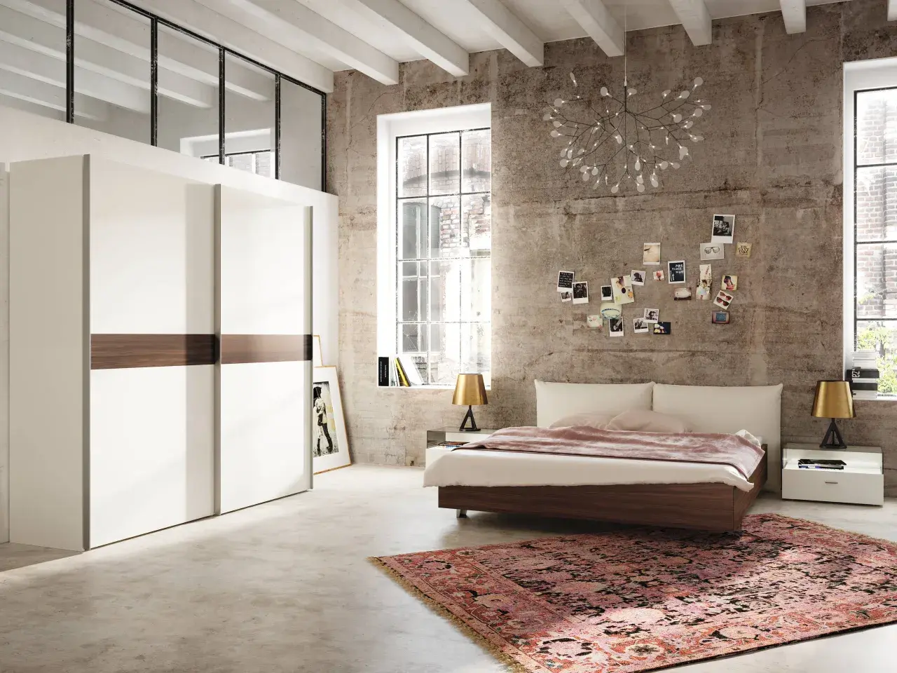 Chambre moderne avec grand placard blanc, lit bas, tapis oriental et mur en béton. Une décoration murale de photos et une lampe originale complètent ce **feng shui chambre**.