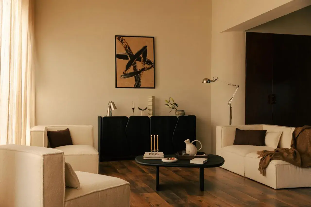 Salon moderne avec fauteuils blancs, buffet noir, tableau abstrait et table basse. Une ambiance chaleureuse pour une deco interieur tendance.