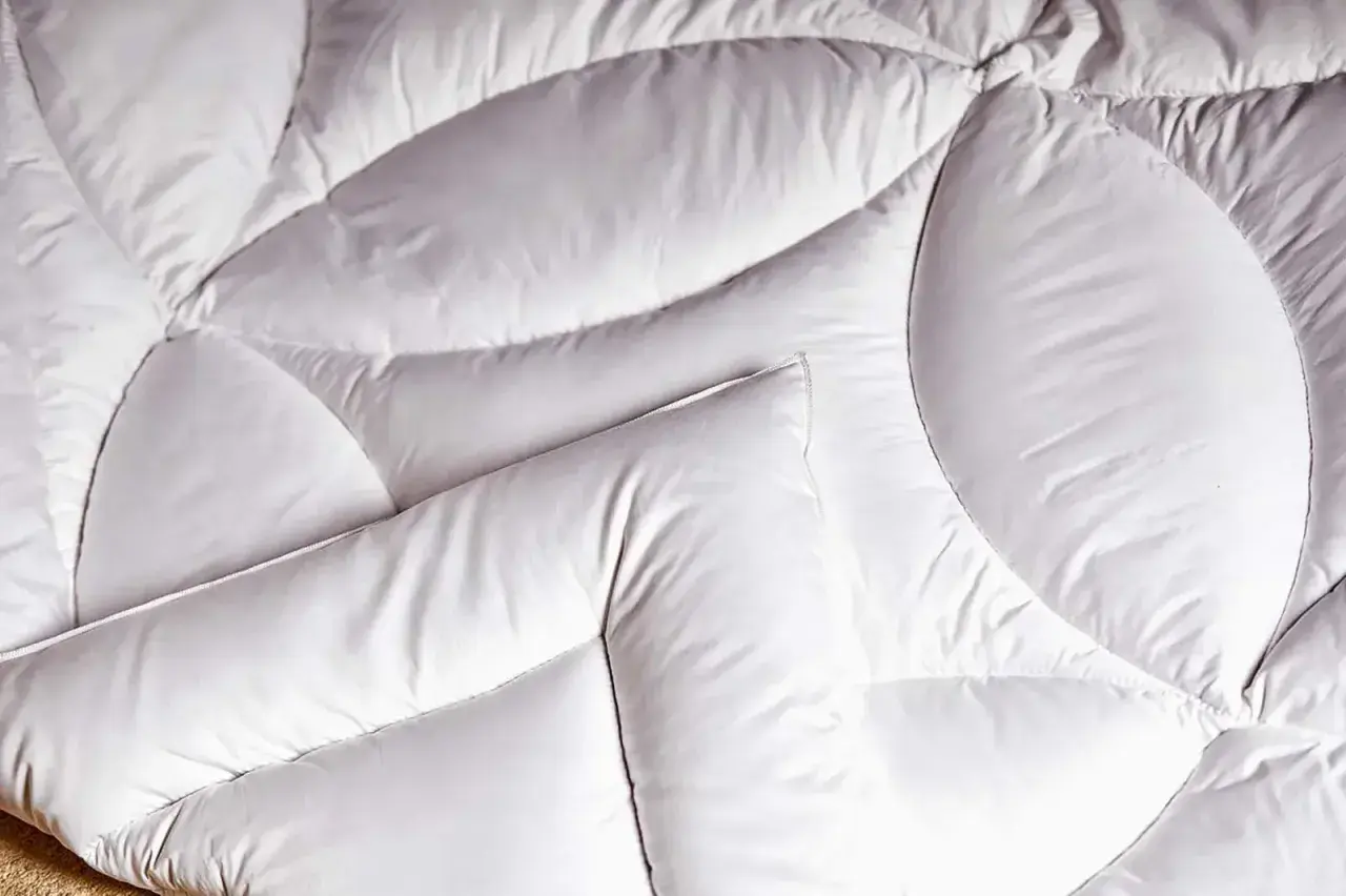 Un édredon blanc, doux et matelassé, prêt à vous envelopper de chaleur. C'est quoi un édredon ? C'est ce confort douillet.