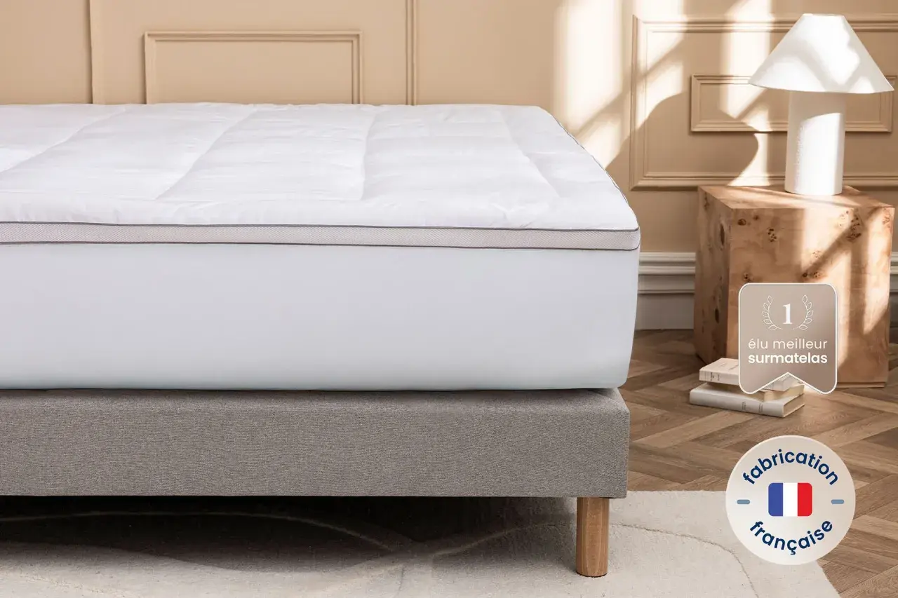 Un surmatelas blanc moelleux sur un sommier gris. Idéal si votre matelas est trop dur que faire ? Fabrication française.