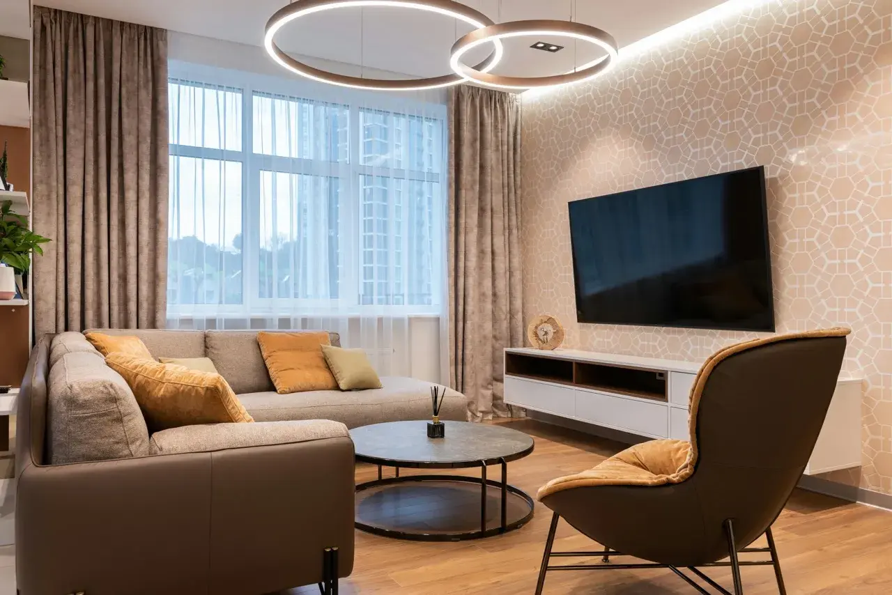 Salon moderne avec canapé, fauteuil, table basse et TV. Le **plan éclairage** met en valeur les suspensions circulaires et l'applique murale.