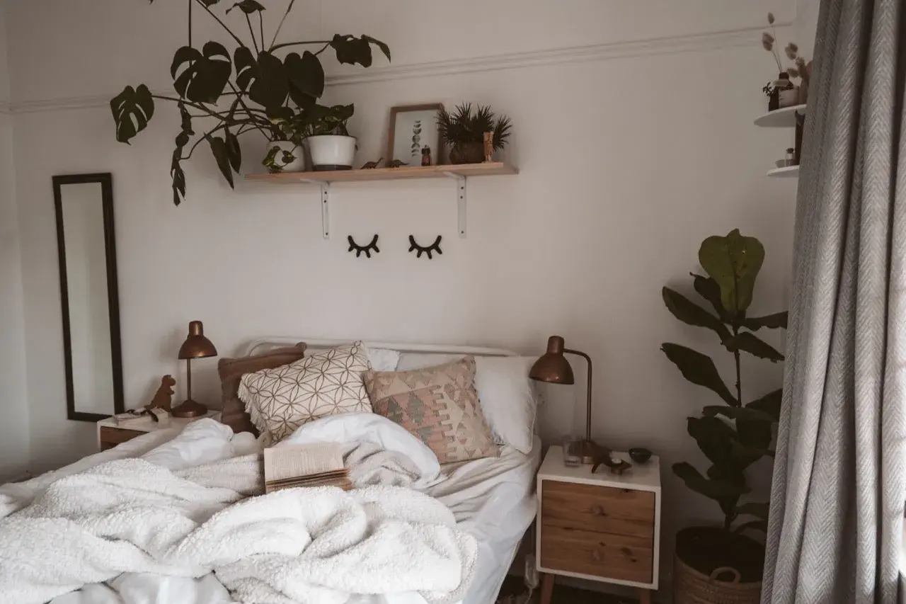 Lit, douillet et plein de verdure, ce lit invite à la détente. Une belle **déco chambre nature** avec des plantes luxuriantes et des coussins texturés.