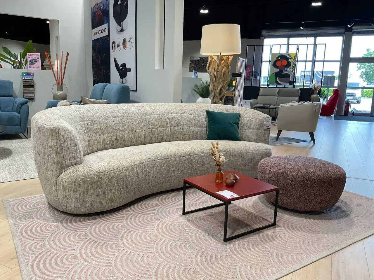 Un canapé courbé et un fauteuil rouge, illustrant la différence entre canapé et fauteuil, dans un showroom de meubles.