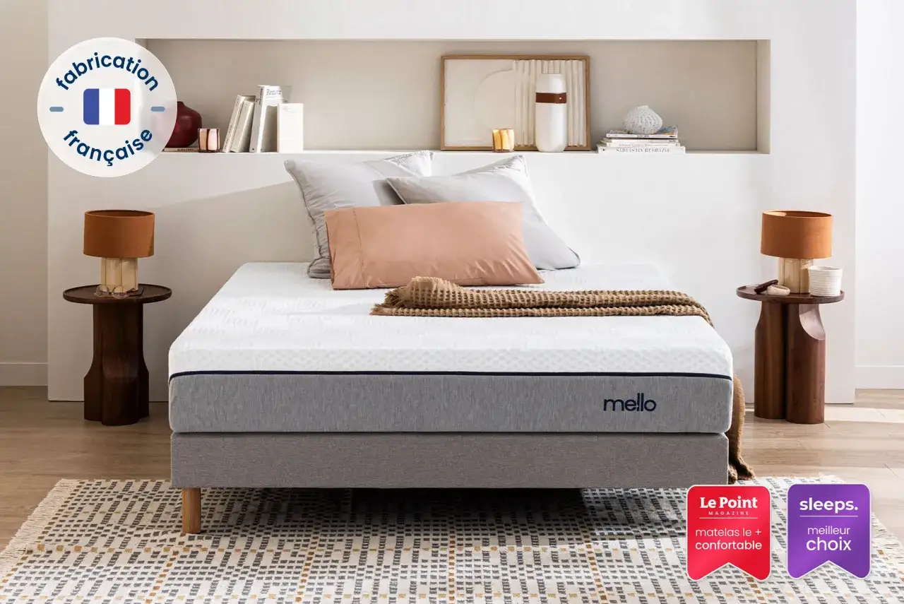 Un matelas Mello, fabrication française, glisse sur son sommier gris. Un plaid douillet est posé dessus.