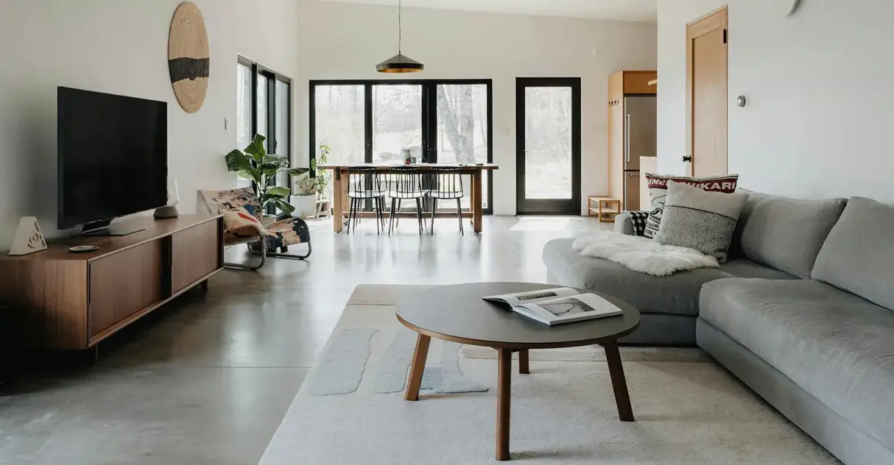 Salon moderne avec une TV sur un meuble bas en bois, un canapé gris confortable et une table basse. La distance entre la tv et le canapé est idéale pour regarder un film.