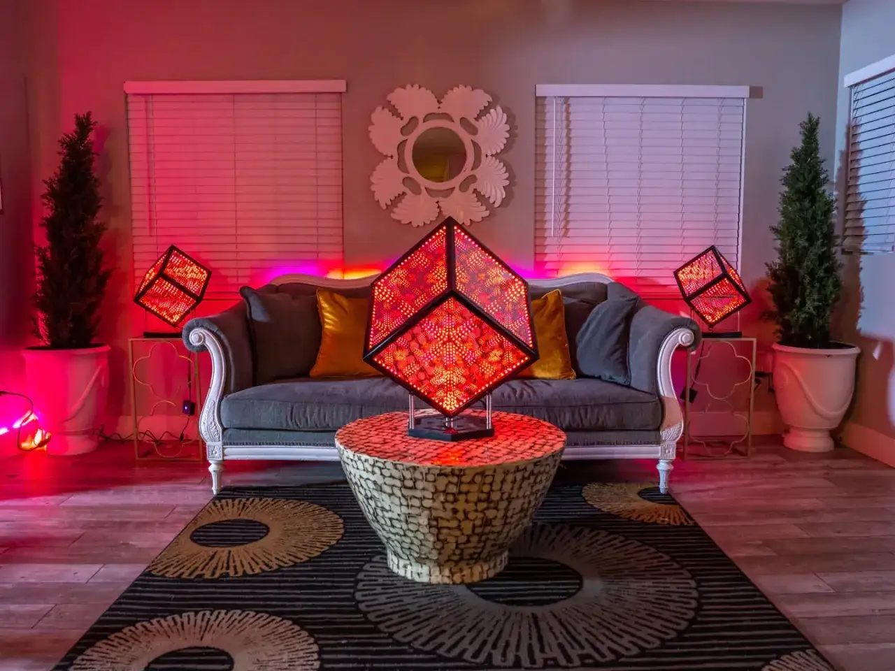 Salon moderne avec canapé gris, coussins dorés et trois lampes cubiques illuminées par des LED rouges. Pourquoi LED ? Pour cette ambiance futuriste !
