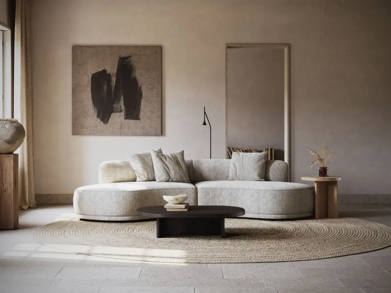 Un salon écru aux lignes douces, avec un canapé arrondi, un tapis rond en jonc de mer et une œuvre d'art abstraite.