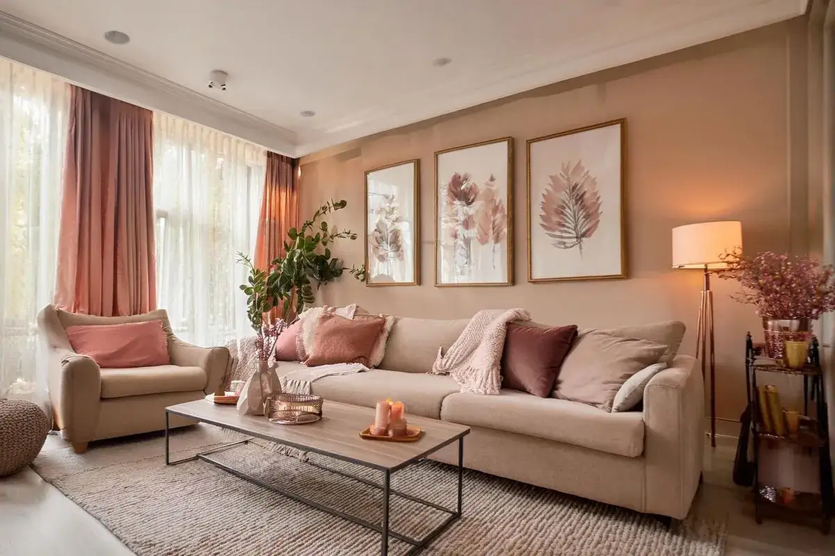 Salon douillet avec canap&eacute; beige, coussins roses, plaids et tableaux de feuilles. Parfait pour une deco appartement cocooning.