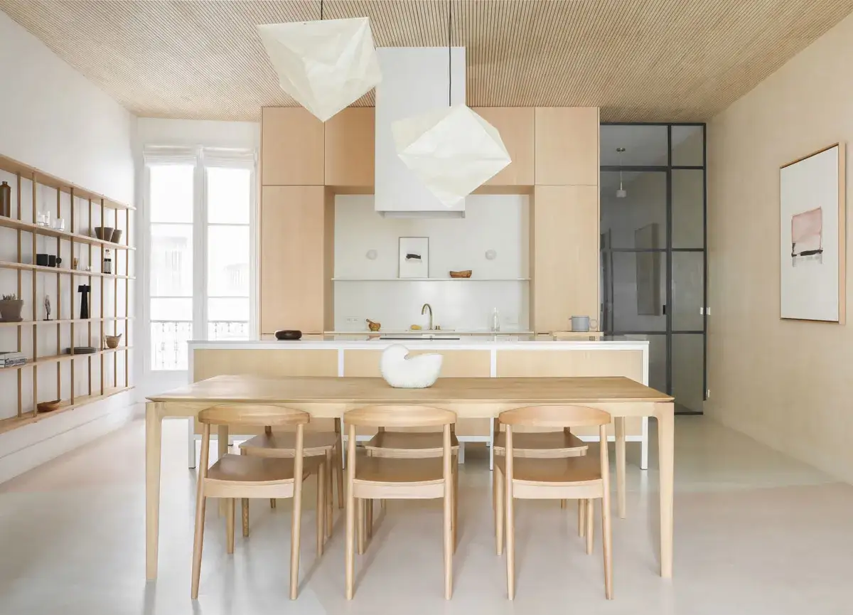 Cuisine lumineuse avec îlot central, table en bois et chaises épurées. Une déco épurée chic qui invite à la convivialité.