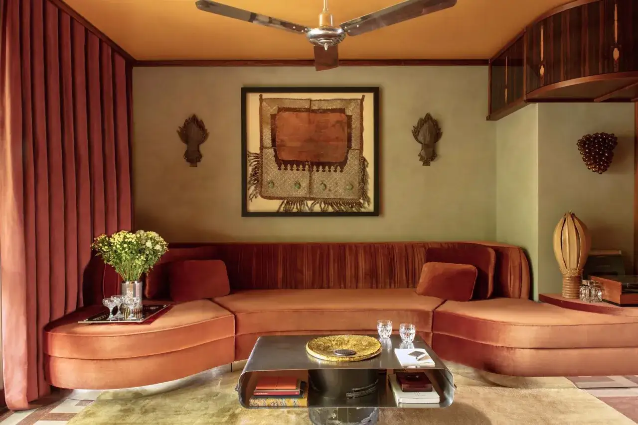 Quel rideau avec mur terracotta ! Un salon chaleureux avec un canap&eacute; orange, une &oelig;uvre d'art ethnique et un plafond jaune.