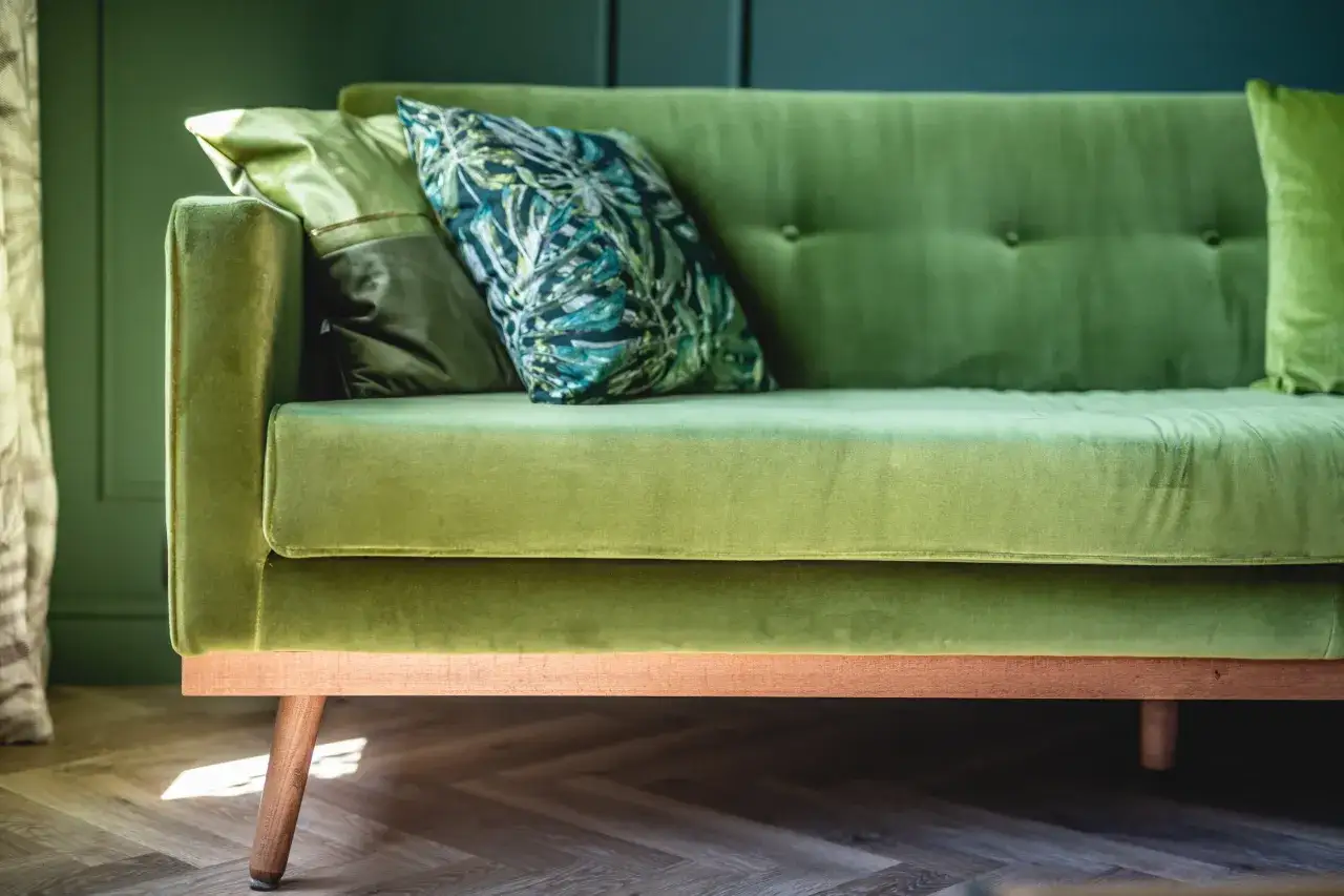 Un canap&eacute; vert velours avec des coussins aux motifs tropicaux. Quelle couleur de rideaux irait avec ce canap&eacute; ?