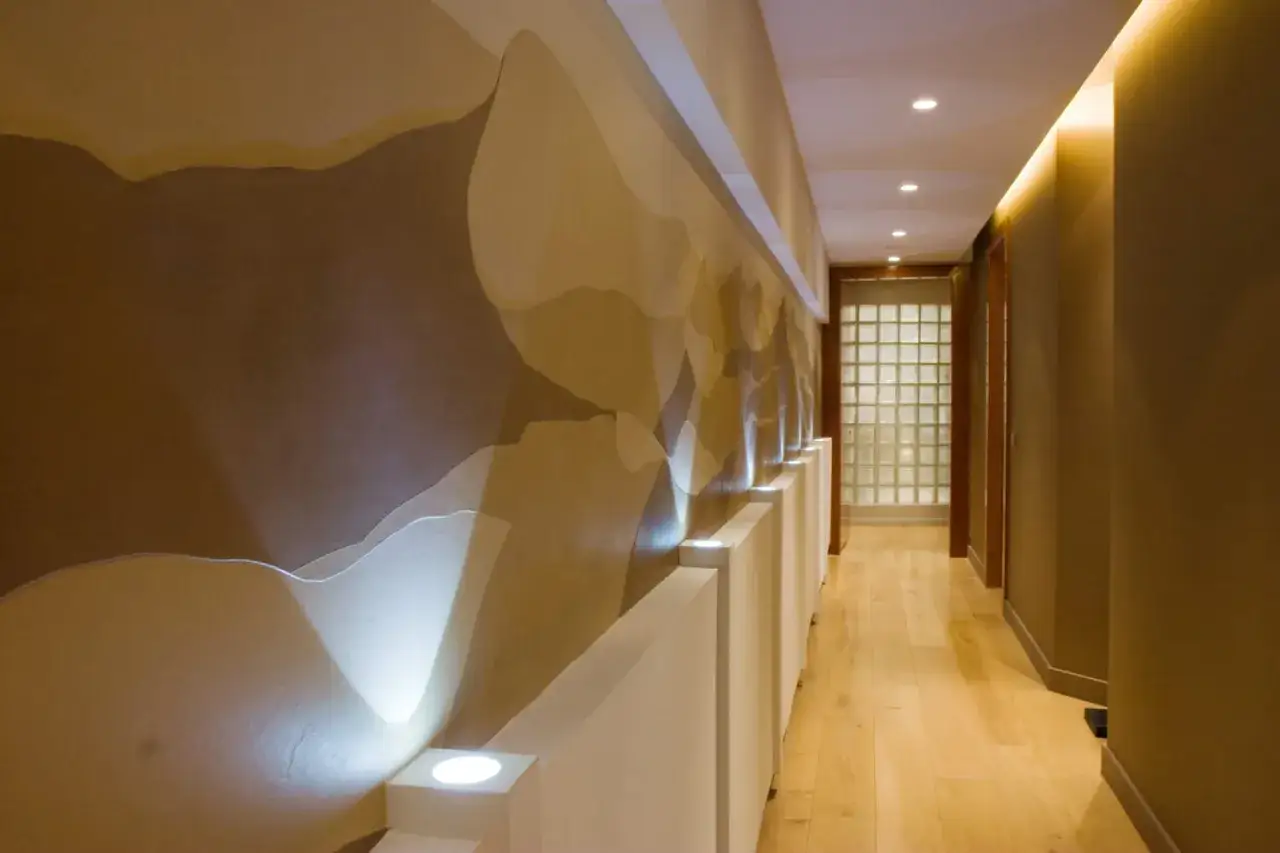 Un couloir sans fen&ecirc;tre illumin&eacute; par des tons chauds et des lumi&egrave;res douces. La paroi textur&eacute;e &eacute;voque des dunes de sable, une belle r&eacute;ponse &agrave; la question : quelle couleur pour un couloir sans fen&ecirc;tre ?