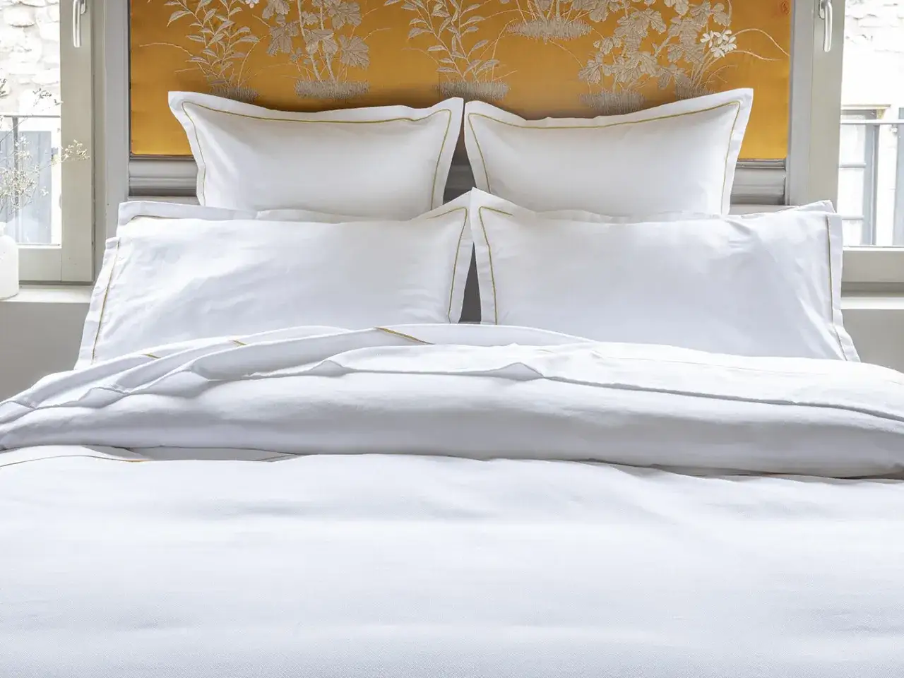 Lit blanc immacul&eacute;, draps et coussins aux finitions dor&eacute;es. Le polycoton, malgr&eacute; son aspect, peut avoir un inconv&eacute;nient : il retient la chaleur.