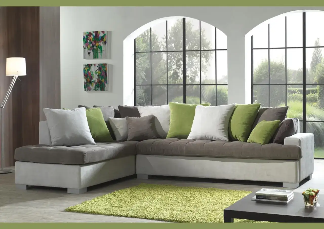 Comment disposer des coussins sur un canapé d'angle : un mélange de gris, blanc et vert pour un look cosy.
