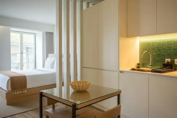Un studio aménagé pour créer une chambre et une cuisine fonctionnelle. Un lit douillet fait face à une fenêtre, tandis qu'une kitchenette moderne est séparée par des cloisons.